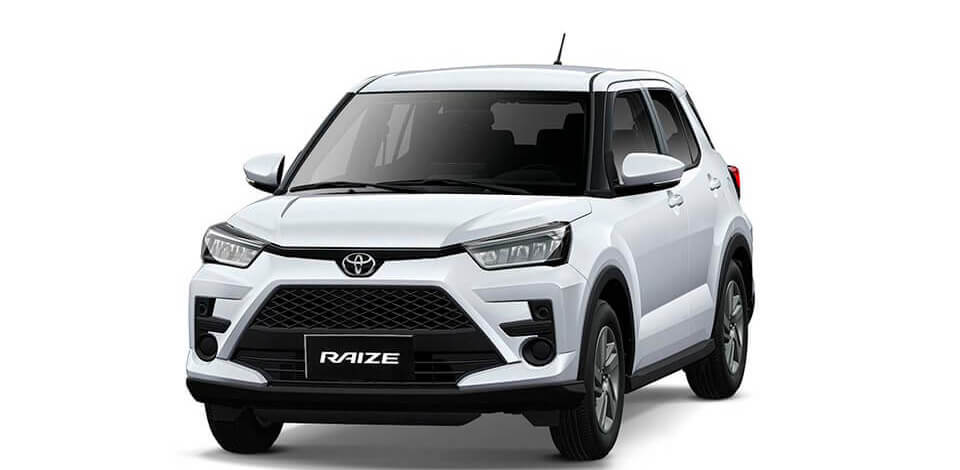 A white modern SUV is parked on a gravel road surrounded by trees, showcasing its tire and wheel detail